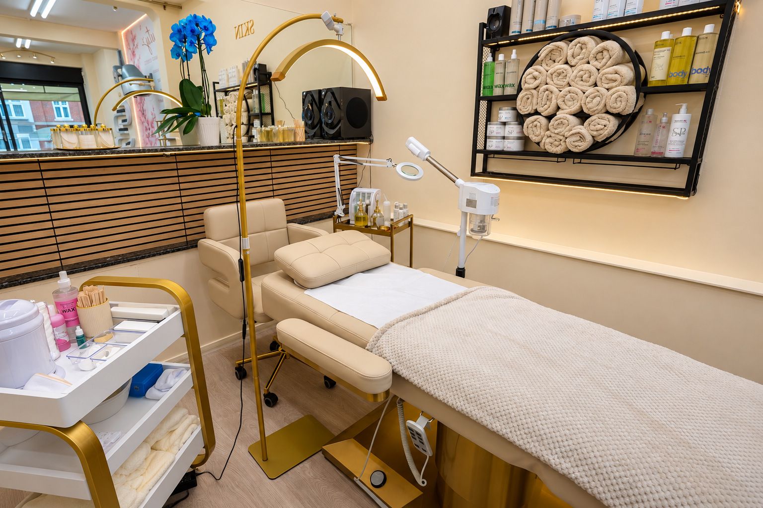 A facial room with a cream treatment couch, magnifying lamp and towel shelf
