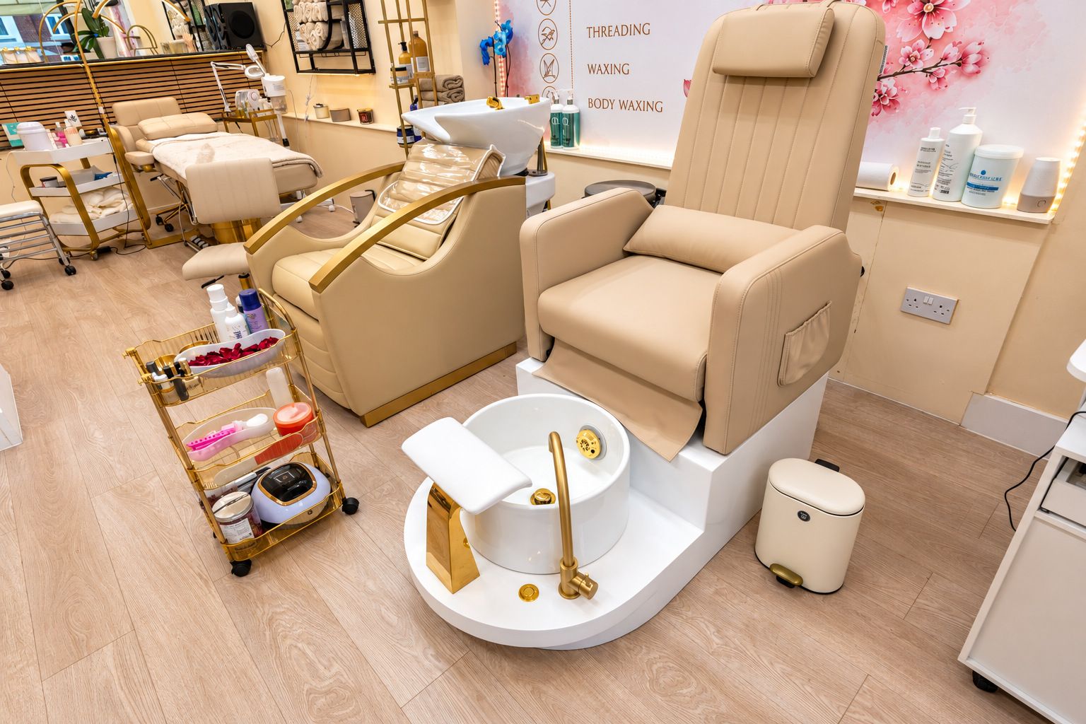 Cream pedicure chairs with white foot basins and gold taps