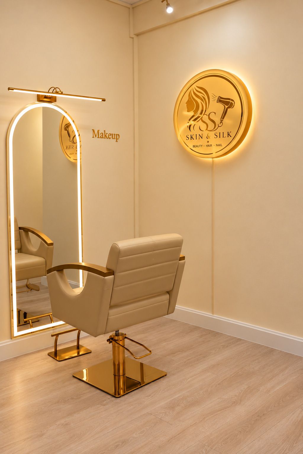 A makeup station with a gold-framed arched mirror and a cream salon chair